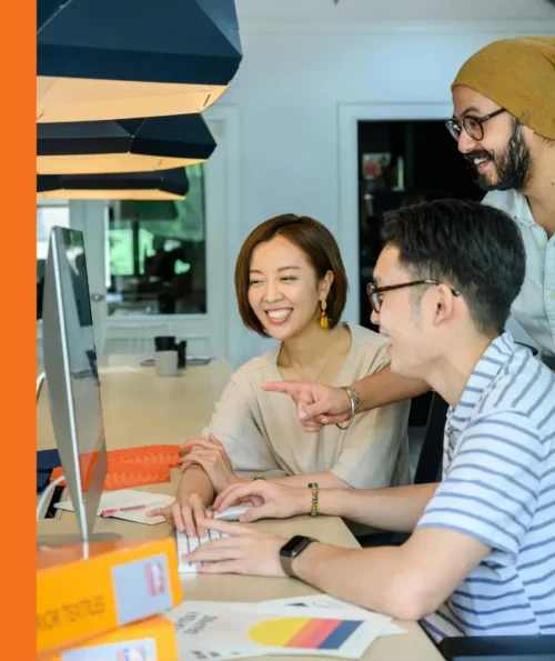 Group of colleagues collaborating and smiling while looking at a computer screen.