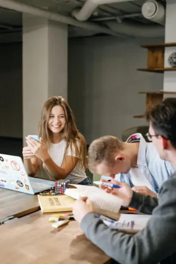 Group of young professionals collaborating at a table with laptops and notebooks.