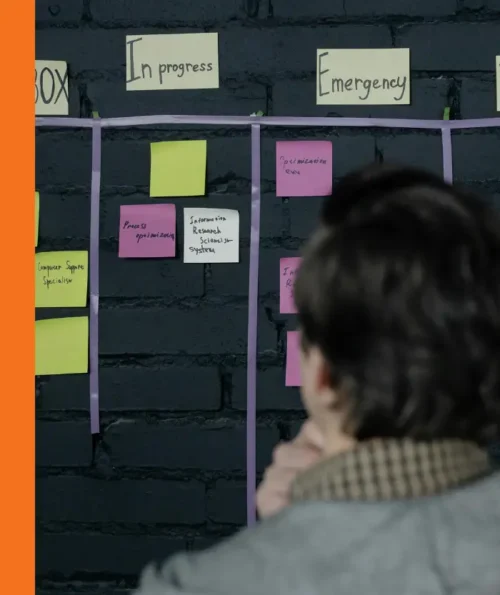 Person observing a task board with categorized sticky notes for project planning.