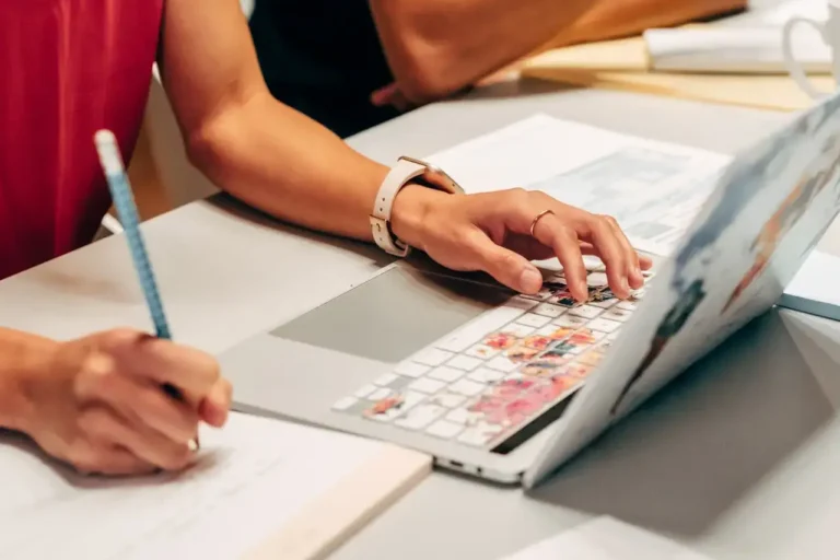 Person working on a laptop and taking notes, representing user research and idea validation