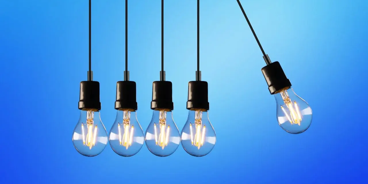 Hanging Lightbulbs Against Blue Background Row of hanging lightbulbs against a gradient blue background