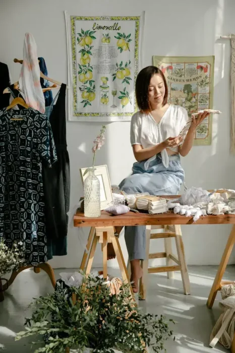 Woman sitting in a creative workspace, surrounded by fabric and art